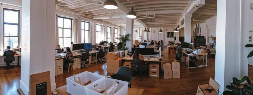a bustling urban office environment where a diverse team collaborates around a sleek conference table, surrounded by moving boxes and digital checklists, embodying the organized chaos of preparing for a smooth relocation.